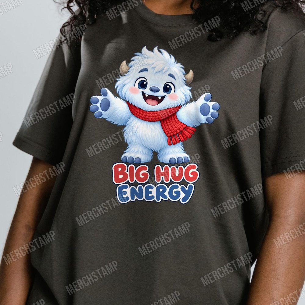 Big Hug Energy PNG design shown on a dark olive t-shirt, a fluffy white yeti in a red scarf with its arms open wide above the words Big Hug Energy