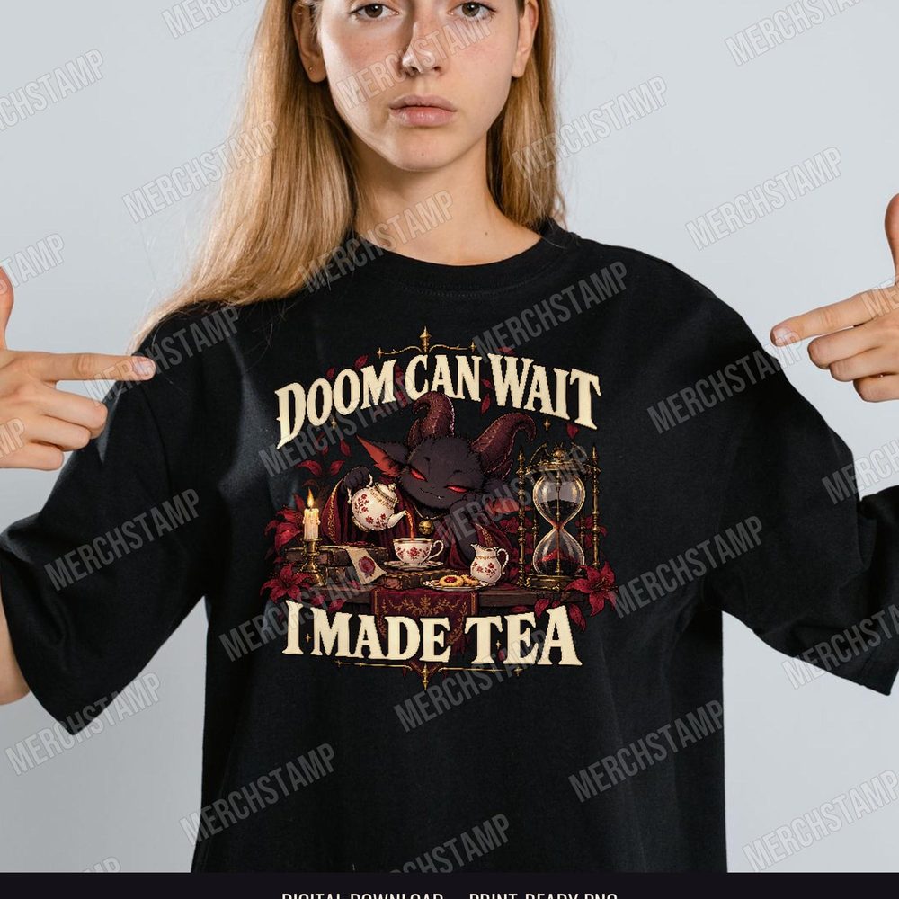 Doom Can Wait I Made Tea PNG design shown on a black t-shirt, a small black horned demon pouring tea beside cookies, a candle and an hourglass between the words Doom Can Wait I Made Tea