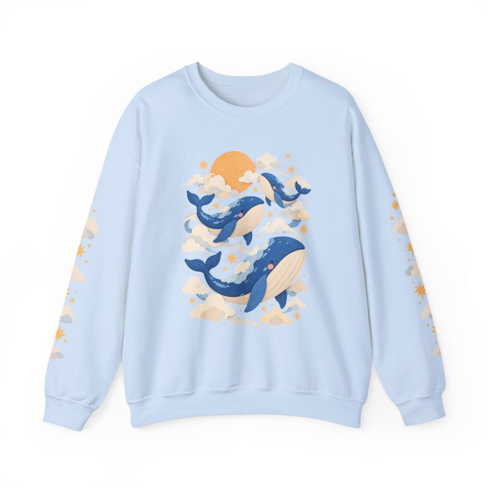 Cloud Whale crewneck sweatshirt in light blue, blue whales swimming through soft clouds under a warm orange sun on the front with matching prints down both sleeves