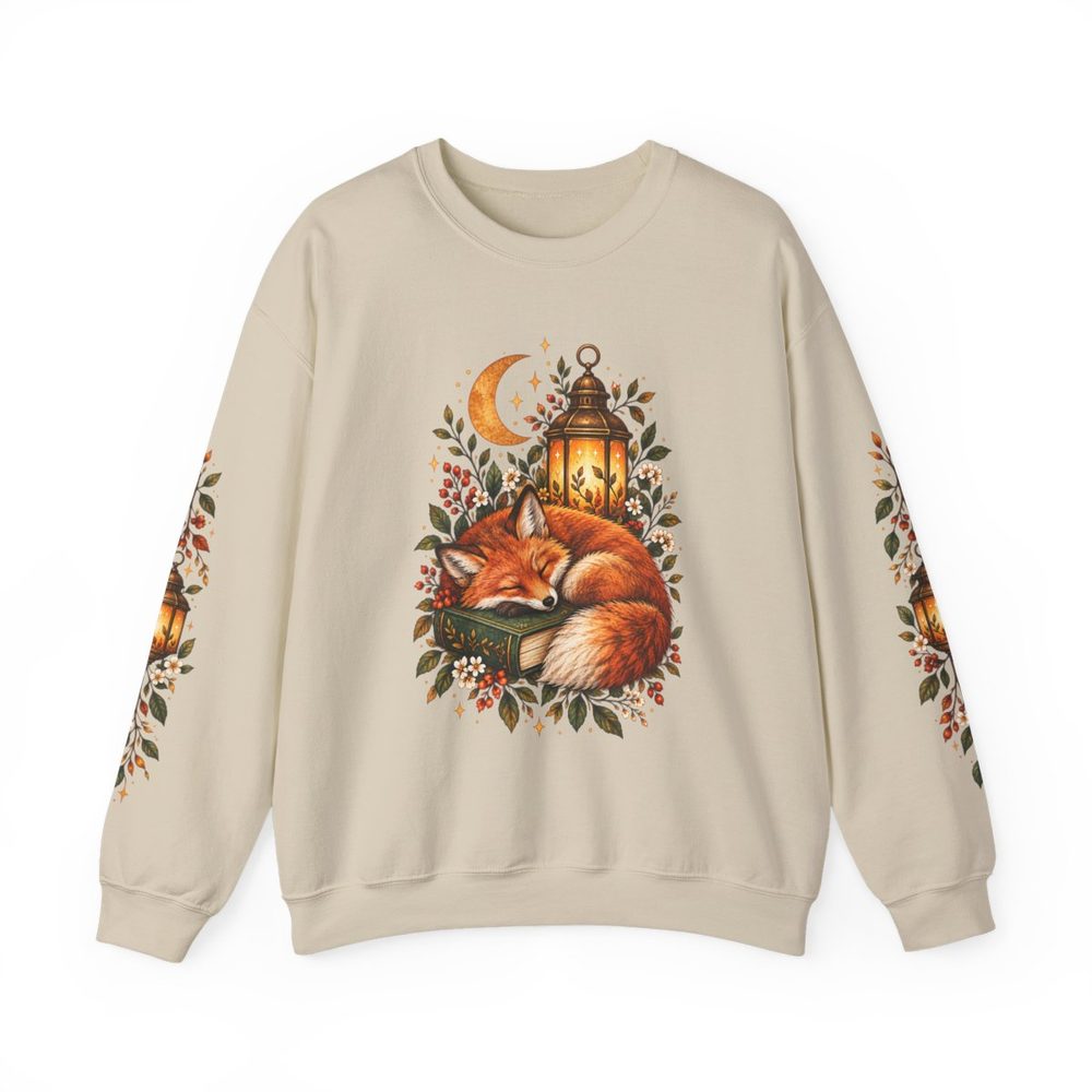 Fox and Lantern crewneck sweatshirt in sand, a curled-up fox beside an open book and an amber lantern among leaves on the front with matching prints down both sleeves